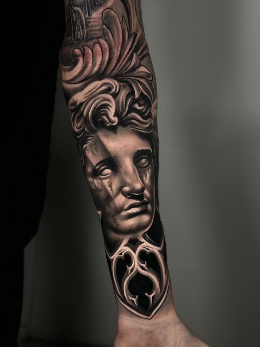 Tatuaje realista de una estatua en el antebrazo